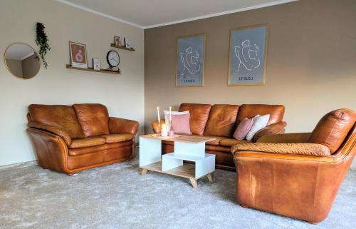a living room with two leather couches and a table at SB Apartment with Sauna in Kołobrzeg
