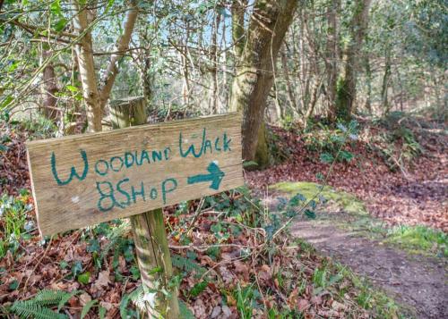 a wooden sign on a trail in the woods at Ruthern Valley Holidays in Withiel