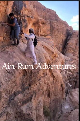 two people are climbing up a rocky mountain at مغامرات عين رم in Jurf ad Darāwīsh