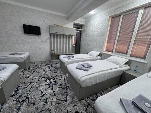 Una habitación con tres camas y un televisor de pantalla plana. en Berkat Boutique, en Bukhara