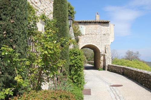 an ivycovered building with an archway and a stone wall at Maison Les Chênes - Jacuzzi - Calme & Idéalement situé - Clim - Salle de Jeux - Parking in Sauzet