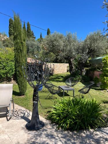 a sculpture in a garden with chairs and a table at Le nid des arts in Tourrettes