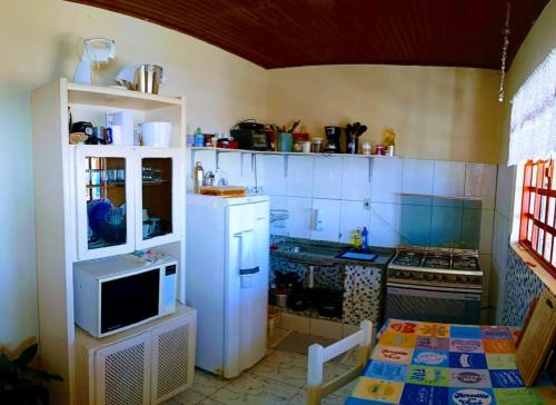 a small kitchen with a stove and a microwave at Portais São Thomé casa de temporada in São Thomé das Letras