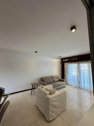 a white living room with a couch and a table at App Queen Kite Village in Uruau