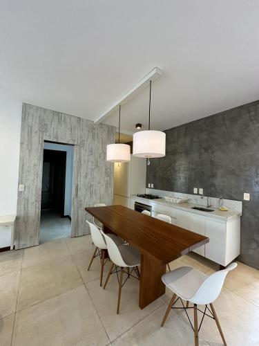 a kitchen with a wooden table and white chairs at App Queen Kite Village in Uruau