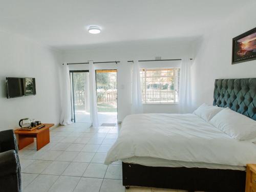 a bedroom with a large bed and a television at Golden Candle Guest House in Roodepoort