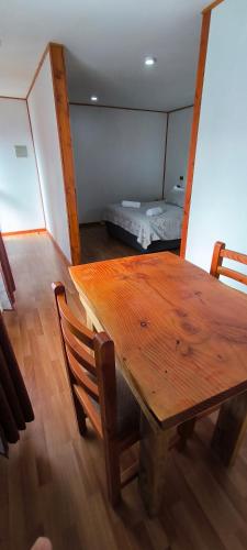 ein Holztisch und Stühle in einem Zimmer mit einem Bett in der Unterkunft Hotel Catripulli in Pucón