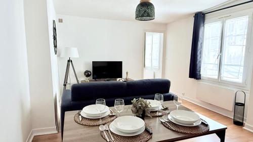 Una sala de estar con un sofá negro y una mesa. en Le Roy Soleil Classé 3 étoiles Cosy & Cœur du quartier Saint-Louis, en Versalles