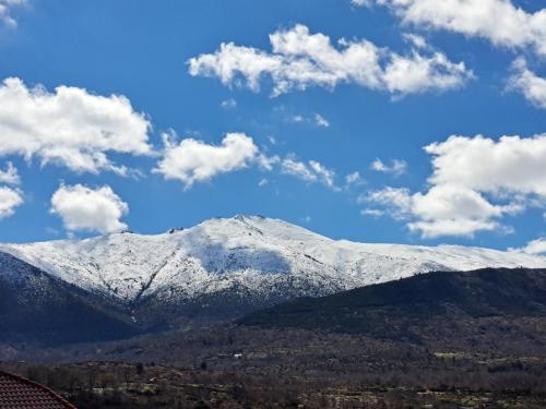 a mountain covered in snow with clouds in the sky at Casa Rural Idesign in Villanueva de Ávila