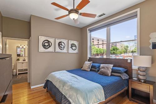 a bedroom with a bed with a ceiling fan and a window at Warehouse District Modern Condo with Private Garage in Raleigh