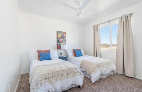 due letti in una stanza bianca con una finestra di Casa Del Sol-Mountain View 3BR Home w Pool Hot Tub a Joshua Tree