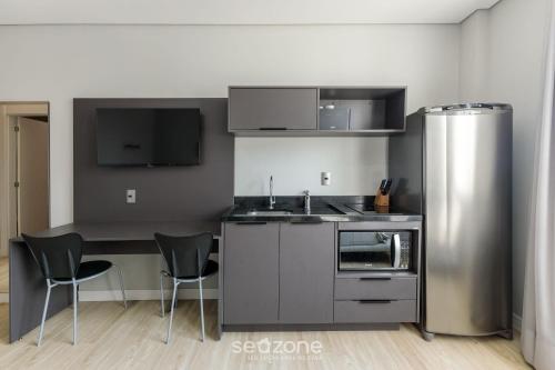 a kitchen with a stainless steel refrigerator and two chairs at TCO - Apartamentos no Centro Histórico Porto Alegre/RS in Porto Alegre