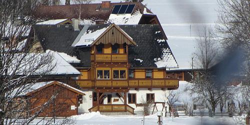 ein großes Holzhaus mit Schnee darauf in der Unterkunft Obergrabnerhof in Ramsau am Dachstein