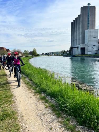 a group of people riding bikes along a river at Place de la gare cy in Commercy
