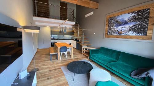 un salon avec un canapé vert et une table dans l'établissement Résidence Loup Dore - Appartement prestige - Plein sud - 90m² - Face aux pistes - 9 Pers. MAE-0243, à Montgenèvre