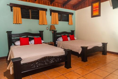 two beds in a room with red pillows at Catarata Eco Lodge in Fortuna