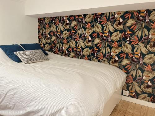 - une chambre avec un lit blanc et un papier peint floral dans l'établissement Rénovation d'architecte dans le cœur historique de Toulouse, à Toulouse