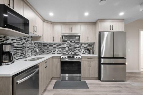 a kitchen with a stainless steel refrigerator and cabinets at Modern 2BR Private Suite NW Near Airport & Amazing Shopping! Free Banff Pass, Netflix, Parking! in Calgary