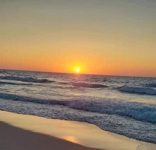 a sunset on a beach with the ocean at شاليه للايجار 3 غرف مكيفات بقرية جراند هيلز الساحل الشمالى بإطلاله مباشره على البول in Qaryat Shurūq