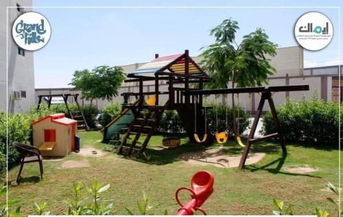 a playground with two swings and a slide at شاليه للايجار 3 غرف مكيفات بقرية جراند هيلز الساحل الشمالى بإطلاله مباشره على البول in Qaryat Shurūq