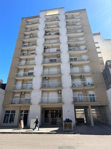 a man walks in front of a tall building at Amplio y céntrico depto de 2 habitaciones opcional cochera in Bahía Blanca