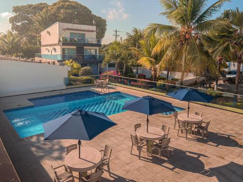 a pool with tables and chairs with umbrellas in front at Cabaña en coveñas en acogedor conjunto residencial in Coveñas