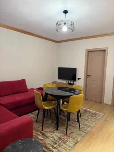 a living room with a table and a red couch at 3Mozaiket Sweet Home in Voskopojë