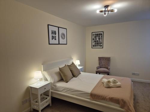 a bedroom with a white bed and a chair at Spacious Modern 2-BR Apartment in Aberdeen City Centre in Aberdeen