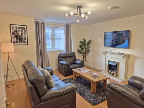 a living room with leather furniture and a fireplace at Spacious Modern 2-BR Apartment in Aberdeen City Centre in Aberdeen