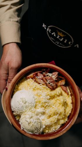 ドボイにあるKraljičini konaciのチーズの入ったボウルを持った人
