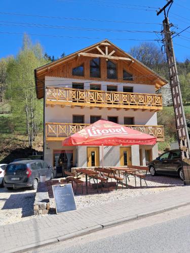 a building with tables and an umbrella in front of it at Pokoje u Daniela in Miedzygorze