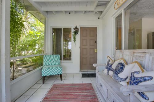 a porch with a bench and a chair at Walk to Ocean Chic Deerfield Beach Cottage! in Deerfield Beach