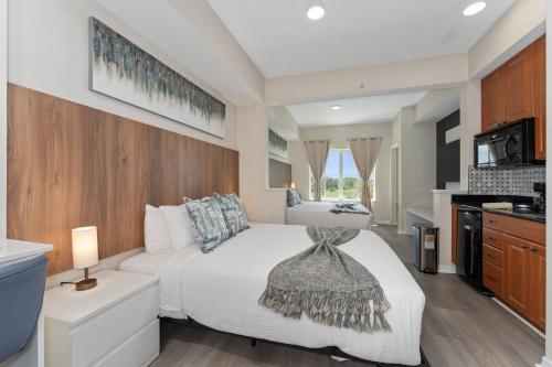 a bedroom with a white bed and a kitchen at 2 Units Together Kitchen Great Location in Orlando