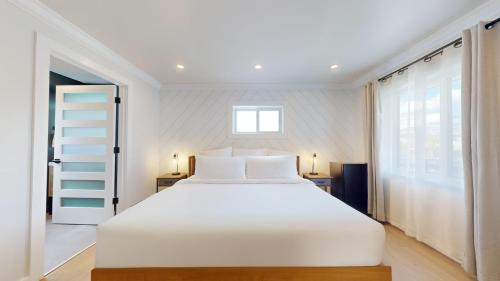 a bedroom with a large white bed and a window at The Surf Club in Ocean City