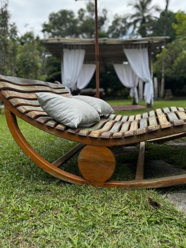 a wooden bench with pillows on the grass at Pousada Casarão de Itaúnas in Itaúnas