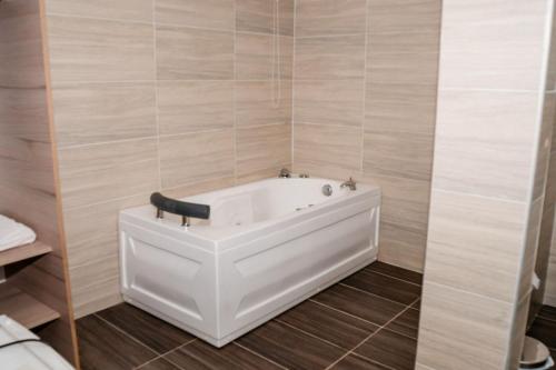 eine weiße Badewanne im Bad mit Fliesenwänden in der Unterkunft BLH Business Loft Hotel in Bucaramanga