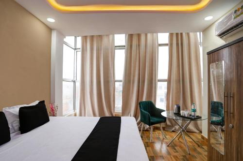 ラクナウにあるHotel O Raisi Residency Hotelのベッドとテーブルと椅子のあるホテルの部屋