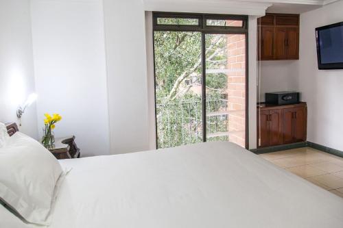 a bedroom with a large white bed and a window at Hotel Casa Laureles in Medellín