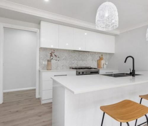 Una cocina con gabinetes blancos y una encimera blanca. en Modern home with Private ensuite, en North Wagga