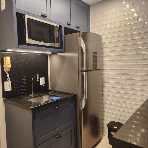 a kitchen with a stainless steel refrigerator and a microwave at FLATS - DUO JK in Sao Jose do Rio Preto
