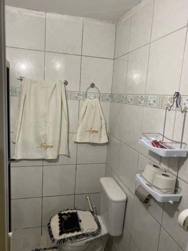 een badkamer met een toilet en handdoeken aan de muur bij Casa Aconchegante Odc in Olho D’Água do Casado