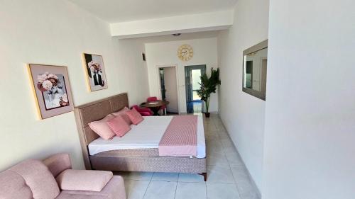 a bedroom with a bed with pink pillows and a couch at Banićević APARTMANI in Ðenovići