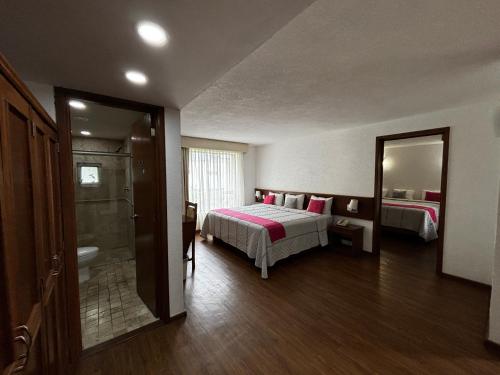 a bedroom with a bed and a bathroom with a mirror at Hotel Quinta Rivera in Actopan