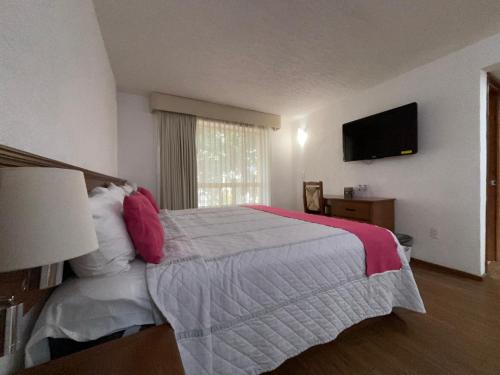 a bedroom with a large bed and a flat screen tv at Hotel Quinta Rivera in Actopan