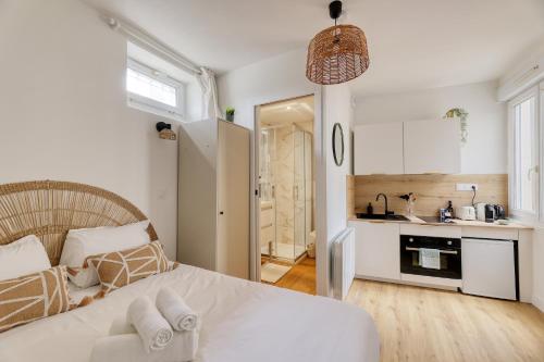Cet appartement comprend une chambre avec un lit blanc et une cuisine. dans l'établissement Studio cosy - entre le Château des Ducs et le Jardin des Plantes, à Nantes
