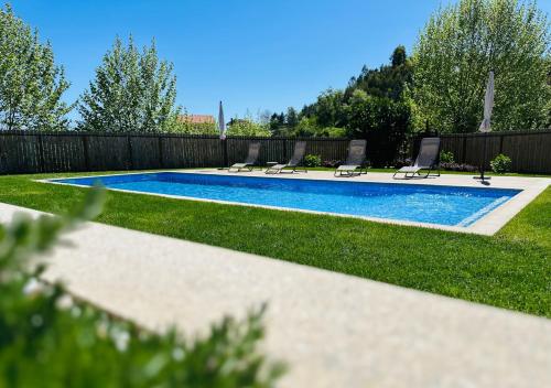 a swimming pool in a yard with chairs and a fence at Casa do Sol e Vinho in Ourilhe
