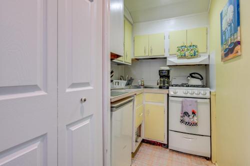 a kitchen with yellow cabinets and a white stove top oven at Less Than 1 Mi to Old Town Lansing Home with Furnished Deck in Lansing