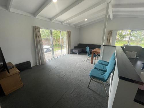 a living room with blue chairs and a table at 3 Bedroom serviced House A, 9 Steeles Lane in Rotorua