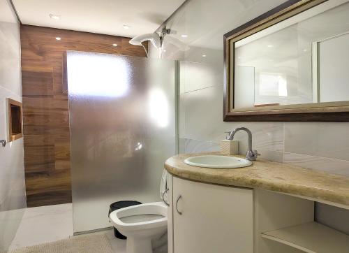 a bathroom with a toilet and a sink and a mirror at Moradas do Campeche CSABC in Florianópolis