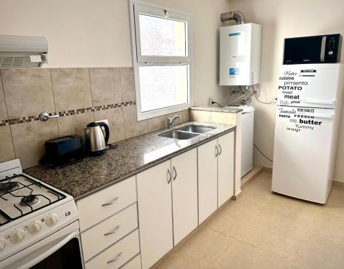 a kitchen with a white refrigerator and a sink at Amplio y céntrico depto de 2 habitaciones opcional cochera in Bahía Blanca